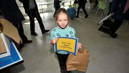 "פרצוף שמח שגם הם יהיו שמחים". ילדה מבית הילדים "עלומים" של קהילת ז'יטומיר באריזת משלוחי מנות. | חב"ד ז'יטומיר