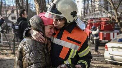עובדת חירום מרגיעה אזרחית שפונתה מבניין בוער בקייב. | AFP עובדת חירום מרגיעה אזרחית שפונתה מבניין בוער בקייב. | AFP