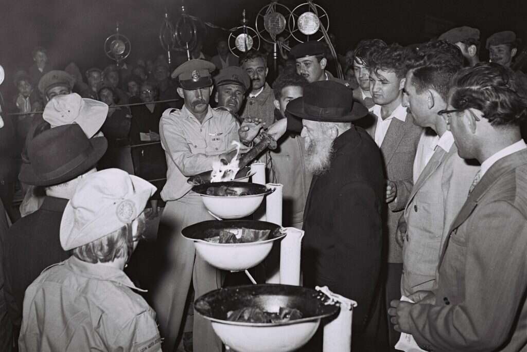 "כל אחד מנסה להגיד מה הוא היה אומר על המצב היום". הרצי"ה מעלה משואה ביום העצמאות 1957. | לע"מ