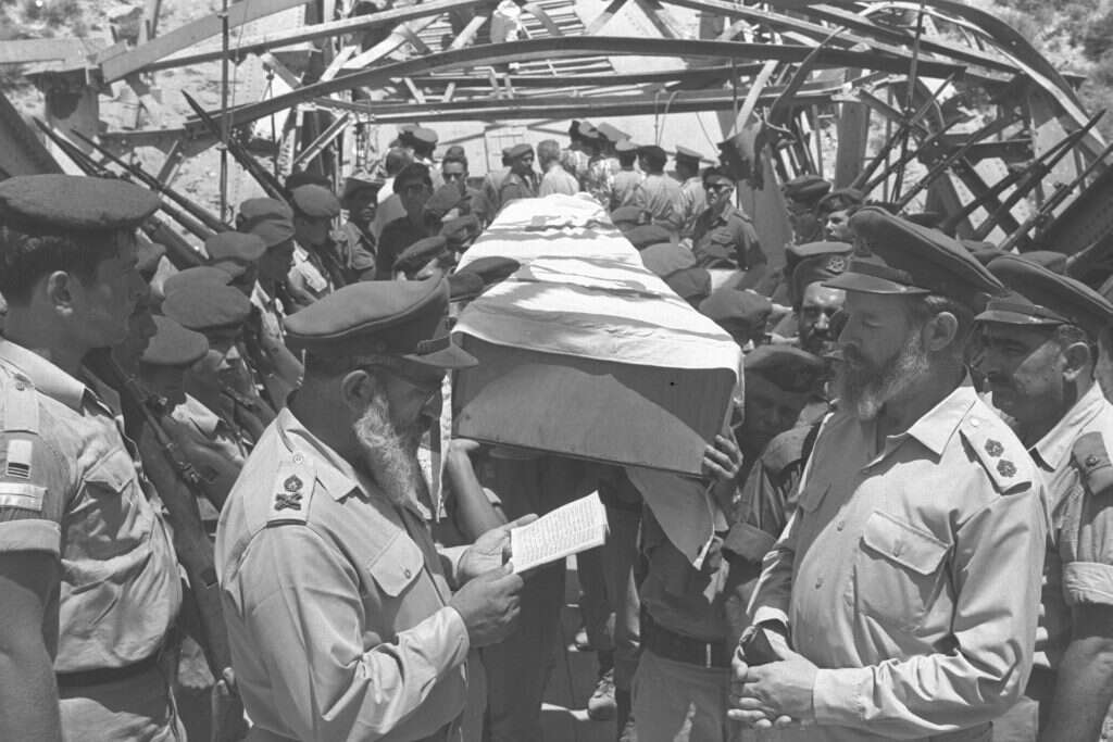 גולת הכותרת של מפעלו ההלכתי: התרת עגונות והבאת גופות חללי צה"ל לקבורה. הרב גורן אומר קדיש על נופלים מחיל האוויר בעת השבת גופותיהם, 1967. | אילן ברונאר, לע"מ