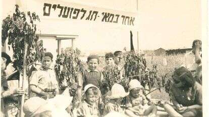 הילד נאלץ להתעטף באדום לכבוד חג הפועלים ואינו יכול לשאת זאת. חגיגת אחד במאי בגן ילדים בקריית־אתא, שנות הארבעים. | בית פישר, קרית אתא