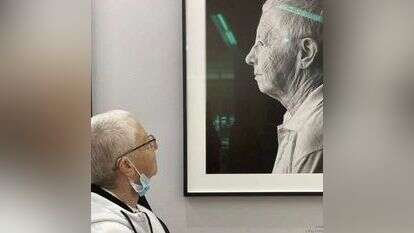 ריטה ארד מביטה בתמונתה המוצגת בתערוכה. | נעם בן־גוריון מוסרי