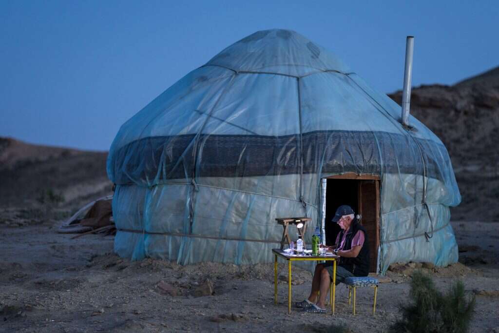 השמש מכתיבה את שעות הפעילות. תייר אוסטרי כותב לצד היורט במחנה היורטים בשעת ערב. | Marcus Westberg, Washington Post
