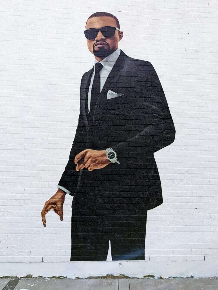 אמן הרחוב כריס דווינס עם ציור הקיר של קניה ווסט על הבניין בשיקגו. קרדיט: כריס דווינס