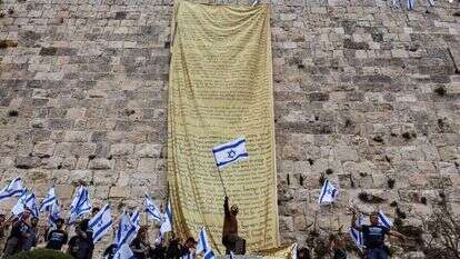 מפגינים תולים את מגילת העצמאות על חומות ירושלים. | רויטרס