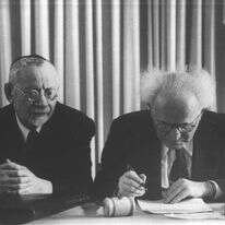 דוד בן־גוריון לצד הרב מימון בחתימה על מגילת העצמאות, 1948. | הנס פיין, לע"מ