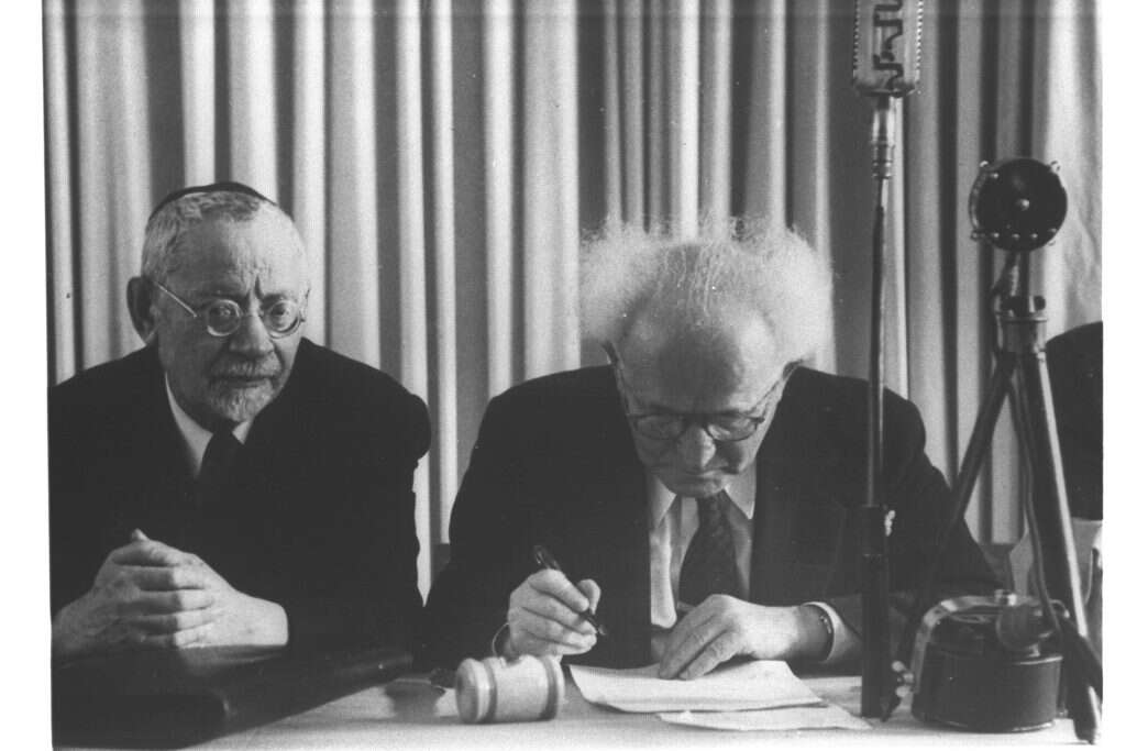 דוד בן־גוריון לצד הרב מימון בחתימה על מגילת העצמאות, 1948. | הנס פיין, לע"מ