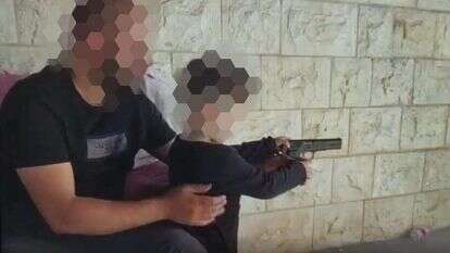 מסך מתוך הסרטון של הדוד שנותן לאחייניו לירות בנשק מסך מתוך הסרטון של הדוד שנותן לאחייניו לירות בנשק