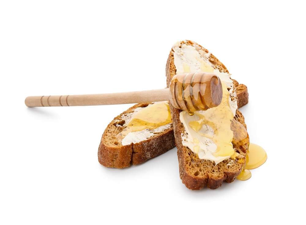 חמאה ודבש על פרוסת לחם. | שאטרסטוק