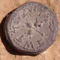 מטבע הכסף כפי שנמצא בשטח. במרכזו של המטבע מופיעים שלושה רימונים - ומסביב הכיתוב ירושלים קדשה. | אמיל אלג'ם, רשות העתיקות