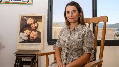 "את הדאגות השארתי אצלי". נאהד ח'יר א־ דין בביתה, על רקע תמונה משפחתית עם מחמוד והילדים. | אייל מרגולין, ג'יני "את הדאגות השארתי אצלי". נאהד ח'יר א־ דין בביתה, על רקע תמונה משפחתית עם מחמוד והילדים. | אייל מרגולין, ג'יני