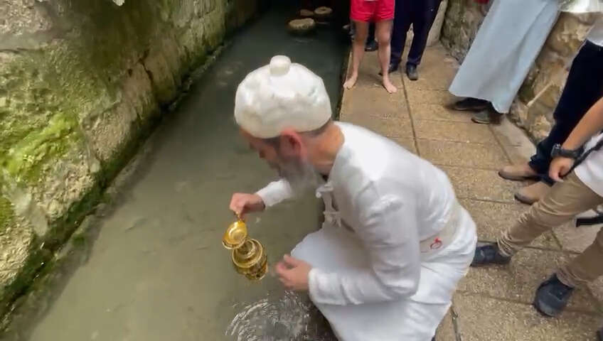 מעמד תרגול ניסוך המים: כוהן בבגדי כהונה ממלא מים מבריכת השילוח. | ג'וש ואנדר