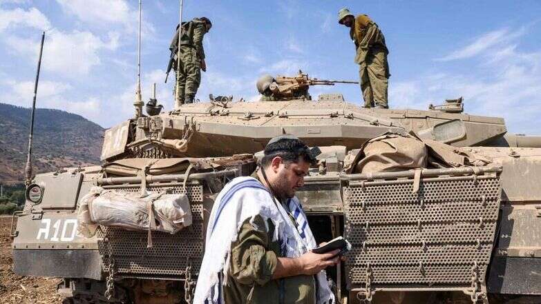 חייל צה"ל מתפלל על רקע הטנק בסמוך לקריית שמונה בגבול הצפון, אוקטובר 2023. | AFP חייל צה"ל מתפלל על רקע הטנק בסמוך לקריית שמונה בגבול הצפון, אוקטובר 2023. | AFP