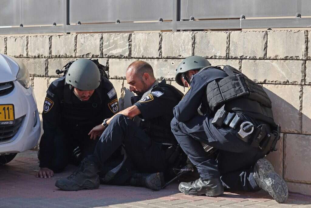 שוטרים תופסים מחסה בזמן ירי רקטות מרצועת עזה על העיר אשקלון. 7 באוקטובר 2023. | AFP