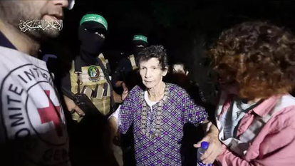 יוכבד ליפשיץ מקיבוץ ניר־עוז עם שחרורה משבי חמאס, כשמחבלי הארגון ברקע. | מתוך הרשתות החברתיות לפי סעיף 27 א' לחוק זכויות יוצרים