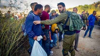 לוחם מאבטח כניסת פועלים פלסטינים למסיק. | נאסר אישתיאה, פלאש 90