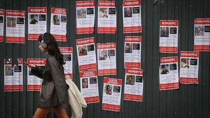 אישה בפריז חולפת על פני כרזות המציגות את החטופים והנעדרים. | אי.אף.פי