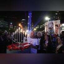 מפוני קיבוץ בארי ומשפחות חטופים בהדלקת נר חנוכה מול הקריה בתל־אביב. | אי.פי.איי