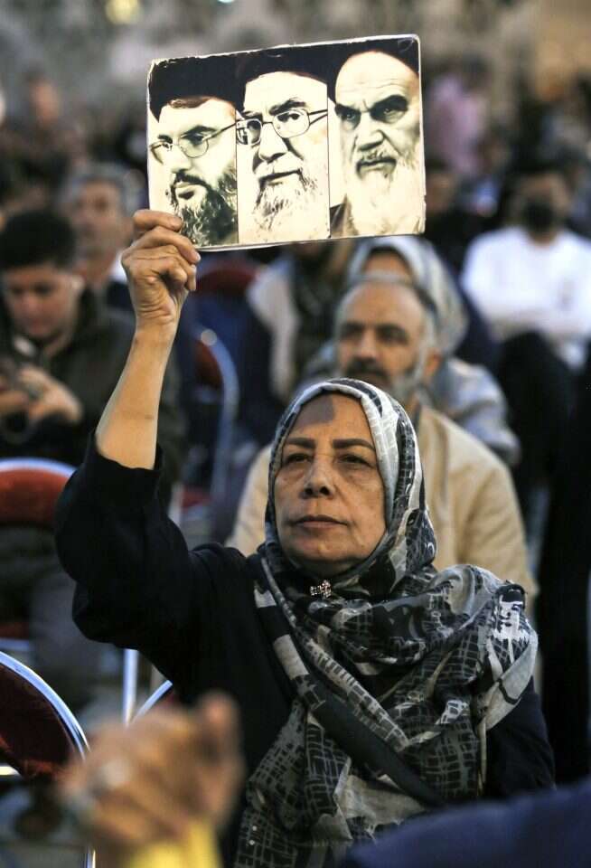"המנהיג הוא הכול". מפגינה איראנית עם תמונות ראשי איראן וחזבאללה. | אי.פי.איי