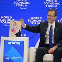 הנשיא הרצוג בפורום הכלכלי בדאבוס עם תמונת התינוק החטוף כפיר ביבס. | עמוס בן גרשון, לע"צ