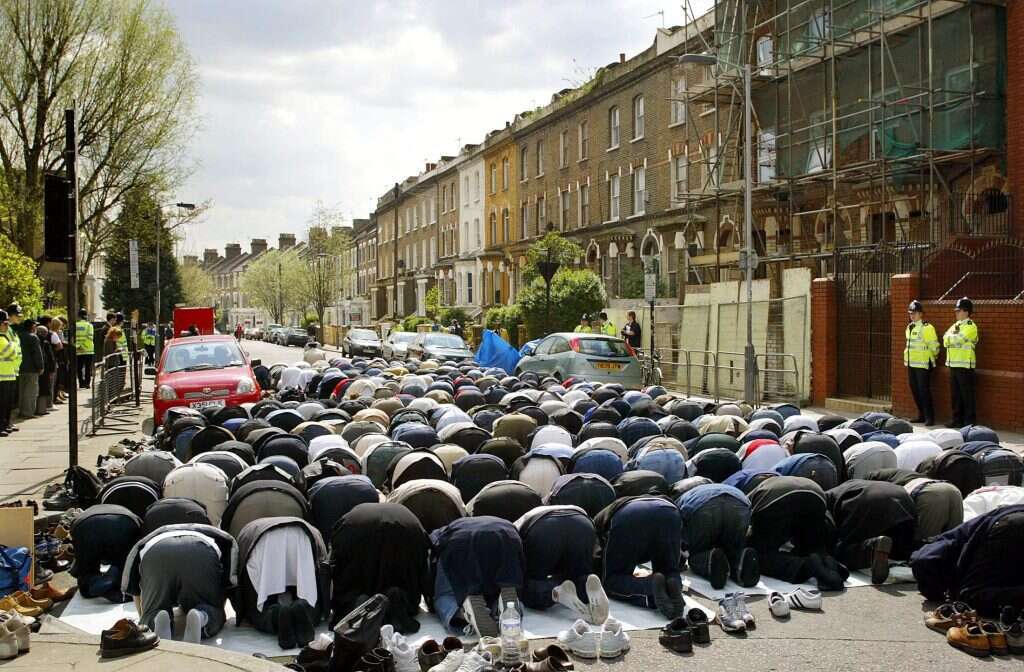 מוסלמים מתפללים ברחוב מגורים מחוץ למסגד פינסברי פארק בצפון לונדון. | איי.אף.פי