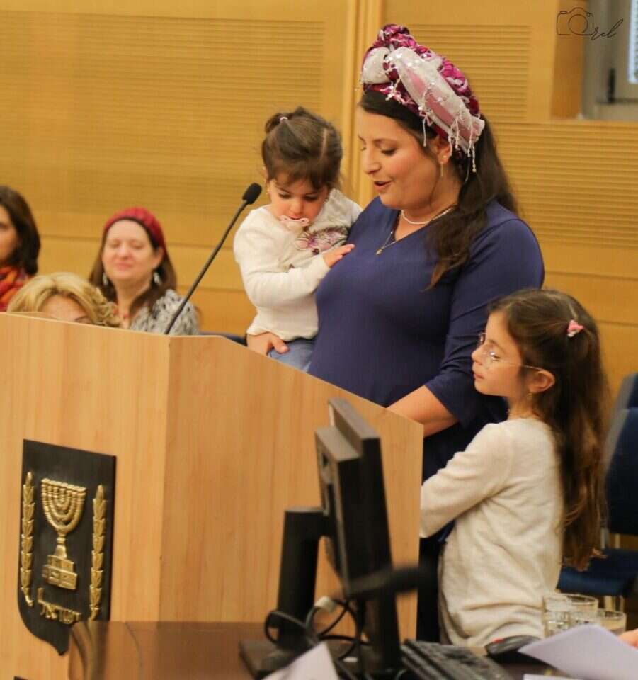 אוריה ברוכי כהן אשת השנה נושאת דברים באירוע החגיגי בכנסת כשהיא חובקת את בנותיה. | תנועת אמונה אוראל קלבו