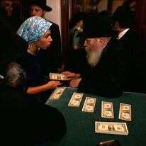 הרבי מלובביץ' מחלק שטרות דולר לאנשי החסידות ב־1991. | גטי אימג'ס