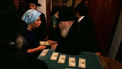 הרבי מלובביץ' מחלק שטרות דולר לאנשי החסידות ב־1991. | גטי אימג'ס