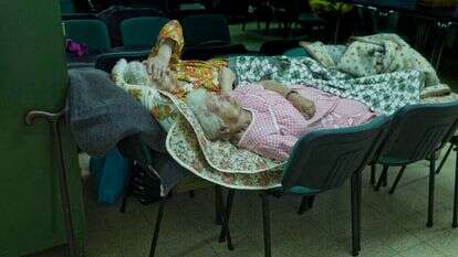 שתי אחיות )ניצולות שואה(, אחת מאשקלון ואחת מבאר שבע, ישנות על כיסאות במבנה ציבורי בזמן מבצע צוק איתן. רינה קסטלנובו, 2014