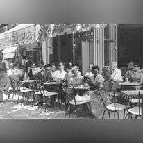 בין בדידות לשותפות, בין אליטה להמון ובין הגברי לנשי. בית קפה בתל־אביב, 1957. | פריץ כהן, לע"מ