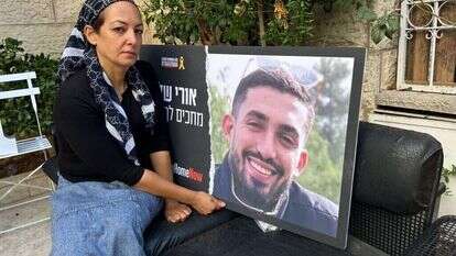 עינב דנינו עם תמונה של בנה אורי ז"ל בחצר ביתה שבשכונת רמות. | עמיאל ירחי