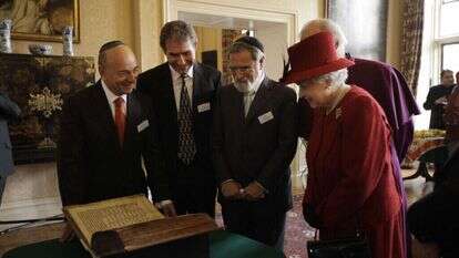 הרב זקס והמלכה אליזבת מתבוננים בכתב היד העתיק ביותר של התנ"ך ששרד באנגליה, הידוע כקודקס ולמדונה I. לונדון, 2012. | אי. אף. פי