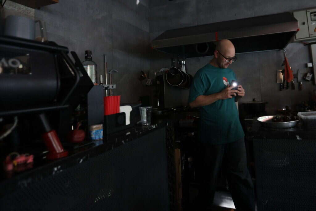 עובד בבית קפה בטהראן מכין הזמנה לאור פנס הטלפון הנייד שלו, בזמן אחת מהפסקות החשמל היזומות באזור. | AFP עובד בבית קפה בטהראן מכין הזמנה לאור פנס הטלפון הנייד שלו, בזמן אחת מהפסקות החשמל היזומות באזור. | AFP