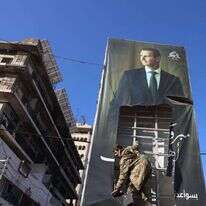 מורד סורי קורע כרזה של נשיא סוריה, בשאר אל-אסד. | EPA