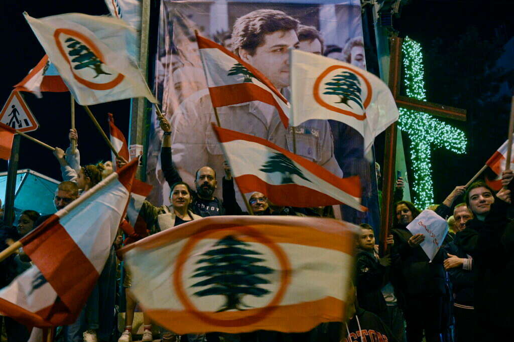לאחר השתלטות המורדים על דמשק, נוצרים לבנונים מניפים דגלים מול כרזה של מייסד הנשיא בשיר גמאייל שנרצח בלבנון.  8 בדצמבר 2024. EPA