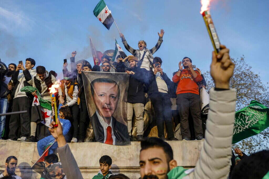 פליטים סורים בטורקיה חוגגים את מפלתו של אסד תוך שהם מנופפים בתמונתו של ארדואן. | אי.אף.פי