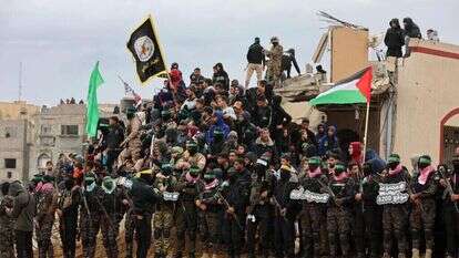 מחבלי חמאס בעת העברת גופות החטופים החללים. | AFP