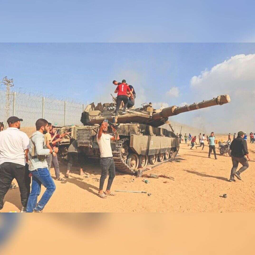 פלסטינים שחדרו לישראל מצטלמים עם טנק של צה"ל, 7 באוקטובר 2023. | AFP