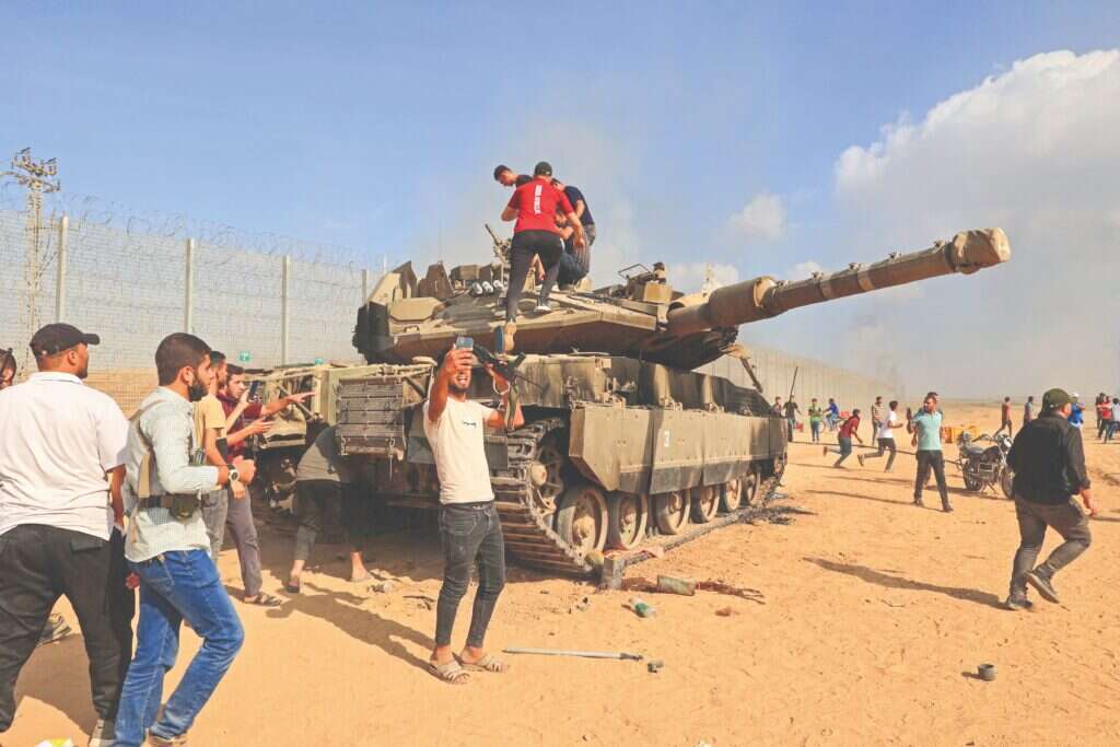 פלסטינים שחדרו לישראל מצטלמים עם טנק של צה"ל, 7 באוקטובר 2023. | AFP