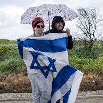 זוג ממתין להגעת גופות ארבעת החטופים הישראלים. | AFP