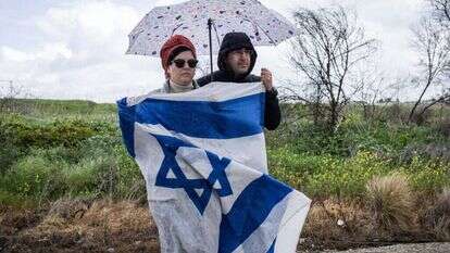 זוג ממתין להגעת גופות ארבעת החטופים הישראלים. | AFP