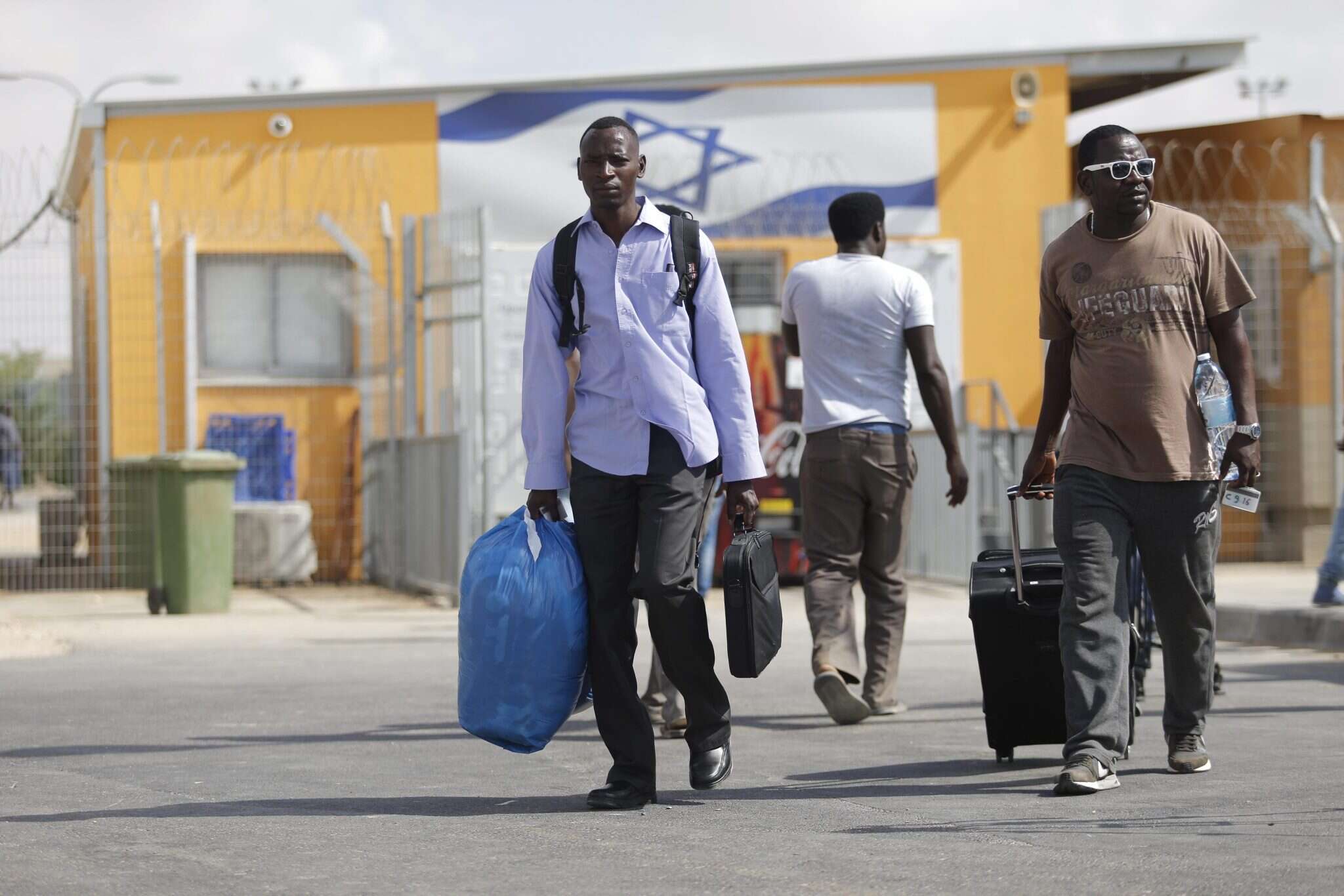 מהגרים מחוץ למתקן חולות. | AFP