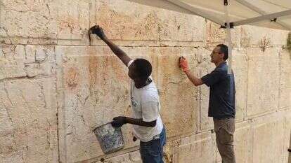 משמרי רשות העתיקות מסירים את הגרפיטי מהכותל | מינהל שימור - רשות העתיקות
