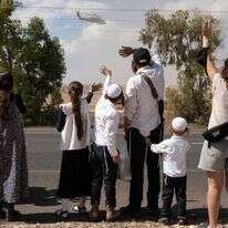 אזרחים סמוך לקיבוץ רעים צופים במסוק עם חטופים ששבו לישראל | AFP