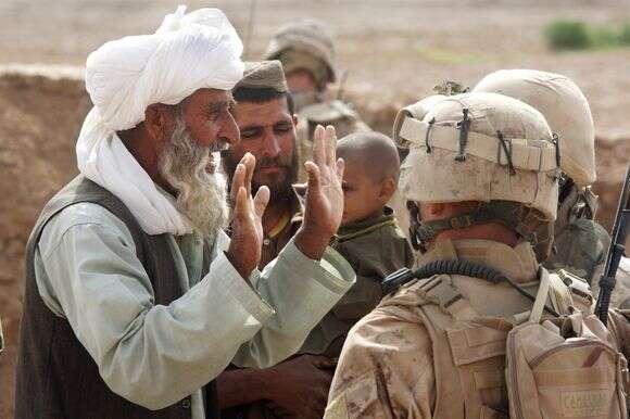 ההוראין העצים את השחיתות בממשל הנשיא. חקלאי מסביר לחיילים אמריקנים שגידול פרג האופיום משמש לרכישת צרכים חיוניים, 2009 | גטי אימג'ס