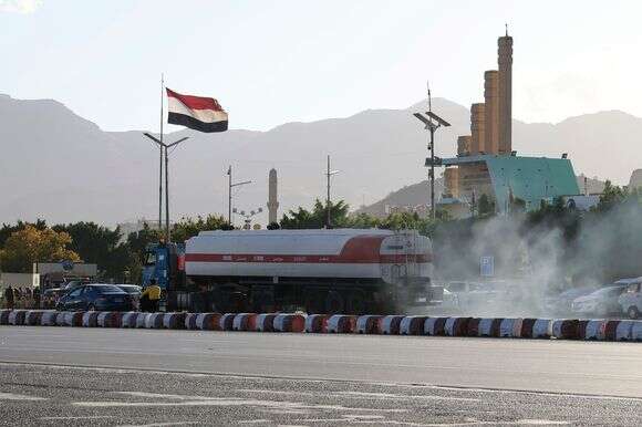 מכלית נפט חולפת על פני דגל תימן מתנופף | EPA/YAHYA ARHAB