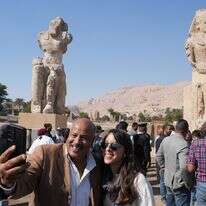 מבקרים מצטלמים עם שני פסלי בהט ענקיים שהורכבו מחדש של פרעה אמנחותפ השלישי, בעיר לוקסור שבדרום מצרים | AP Photo/Amr Nabil מבקרים מצטלמים עם שני פסלי בהט ענקיים שהורכבו מחדש של פרעה אמנחותפ השלישי, בעיר לוקסור שבדרום מצרים | AP Photo/Amr Nabil