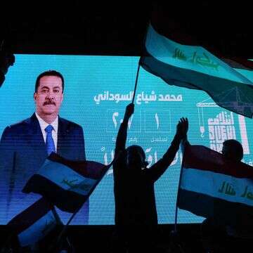 תומכיו של ראש ממשלת עיראק המכהן, מוחמד שיעה אל-סודאני, מנופפים בדגלי המדינה מול מסך המציג את דיוקנו וחוגגים לאחר פרסום תוצאות הבחירות הראשוניות בבגדד | אחמד אל-רוביי / AFP