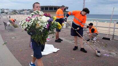 עובדים אוספים פרחים, הודעות תמיכה ופריטים שהושארו בעת פירוק אנדרטה בסידני | AP Photo/Rick Rycroft