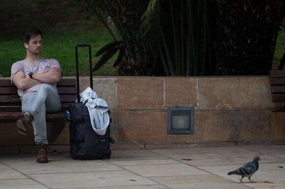 תייר יושב ליד מזוודתו במלאגה | חורחה גררו / AFP